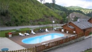 Ein Pool mit Liegestühlen und einem Holzzaun, umgeben von einer hügeligen Landschaft.