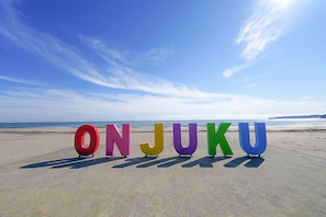 Large colorful letters spelling "ONJUKU" on a beach with a clear sky. - THE ONJUKU terrace (Onjuku)