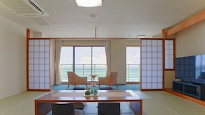A modern hotel room with a large window, a dining table, two chairs, a TV, and a traditional Japanese sliding door. - THE ONJUKU terrace (Onjuku)
