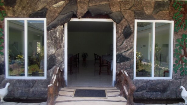 A stone archway entrance to a building with a dining area visible inside.
