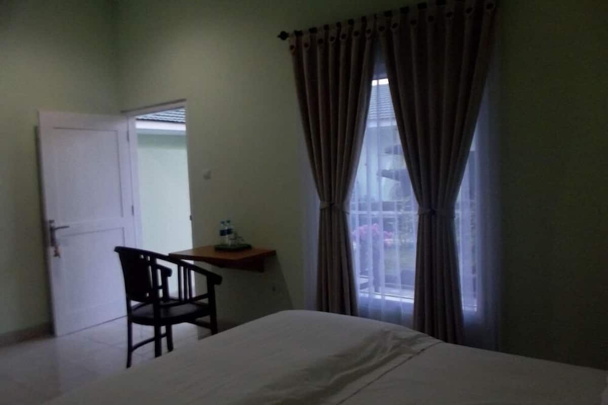 Une chambre Ă coucher avec un lit, une chaise, un bureau et une fenĂȘtre avec des rideaux.