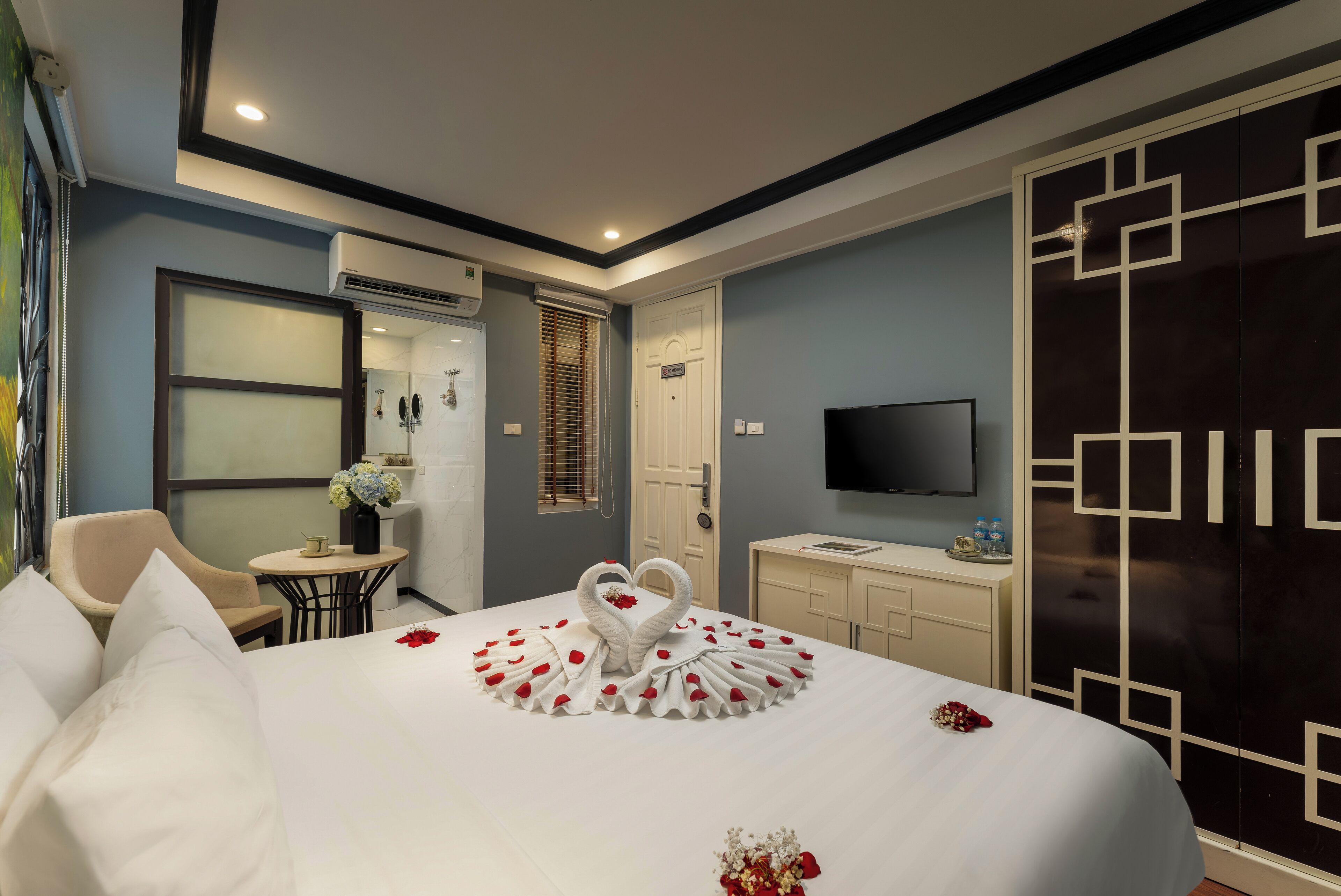 Ein Hotelzimmer mit Bett, Fernseher, Schreibtisch, Stuhl und Kleiderschrank.