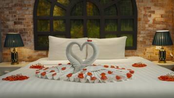 A hotel room with a large arched window, a bed with white linens, and two bedside lamps.