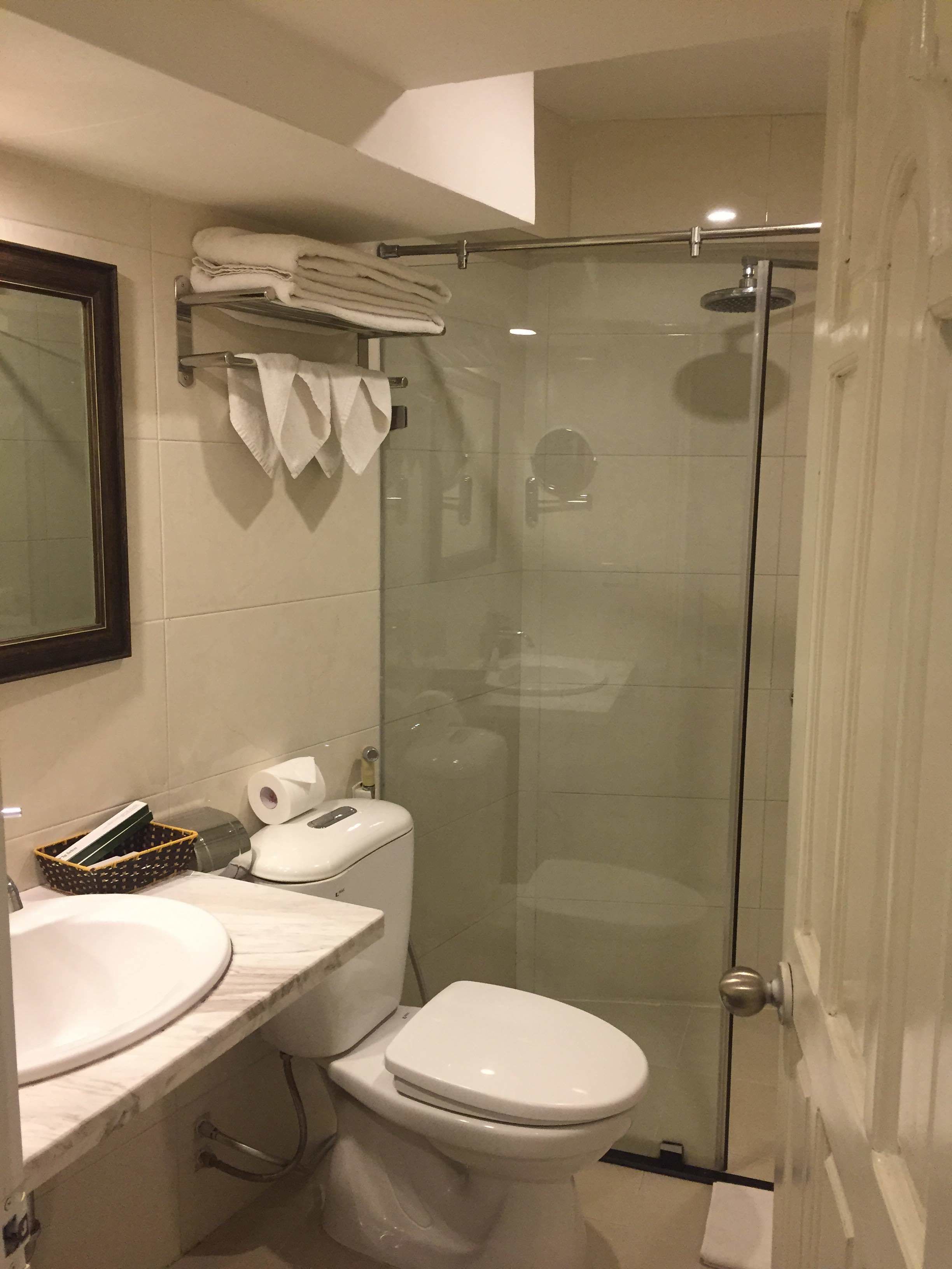 Et badeværelse med toilet, håndvask og brusekabine i glas.