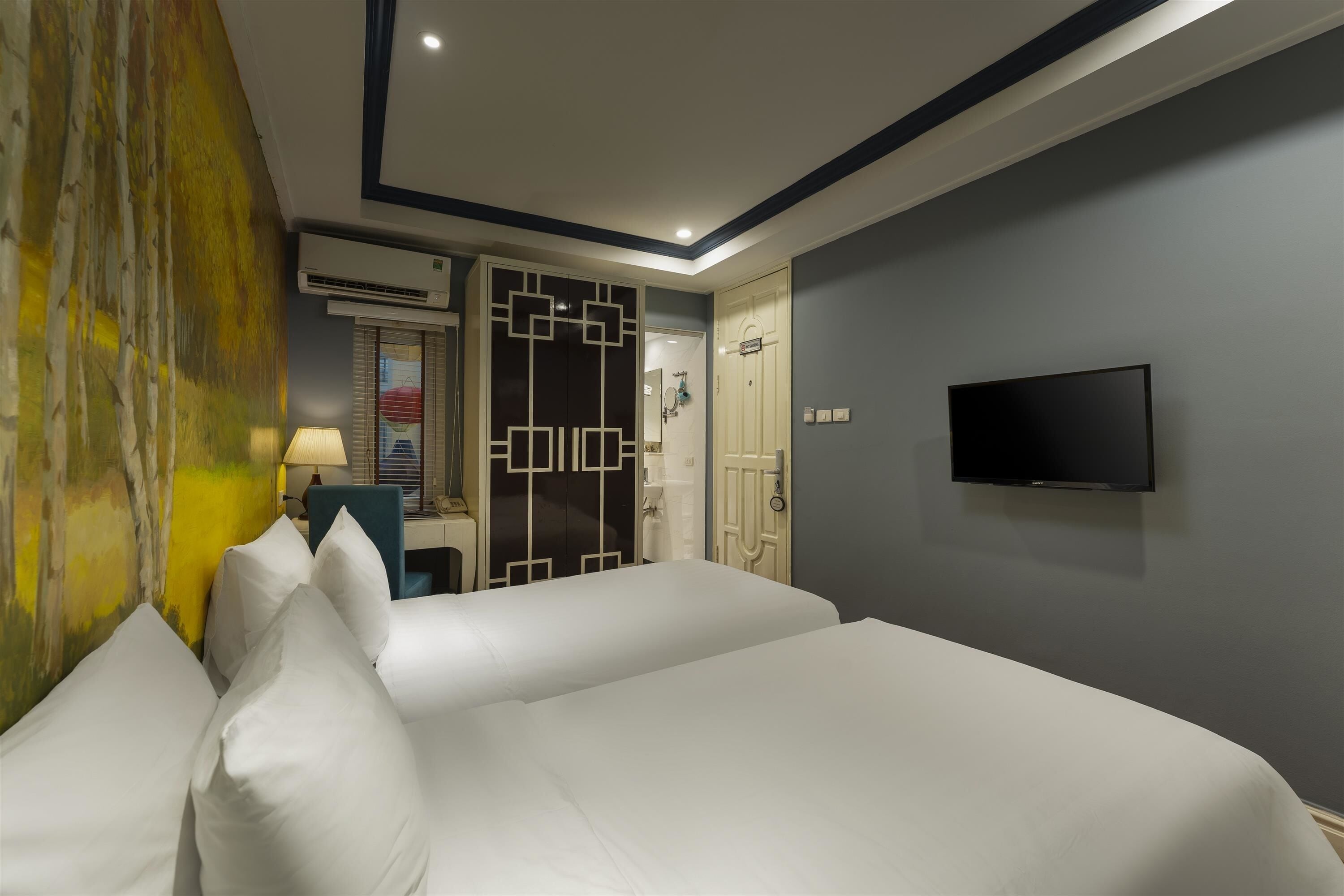 Camera d'albergo con un letto grande, una TV montata a parete e un armadio dal design geometrico.