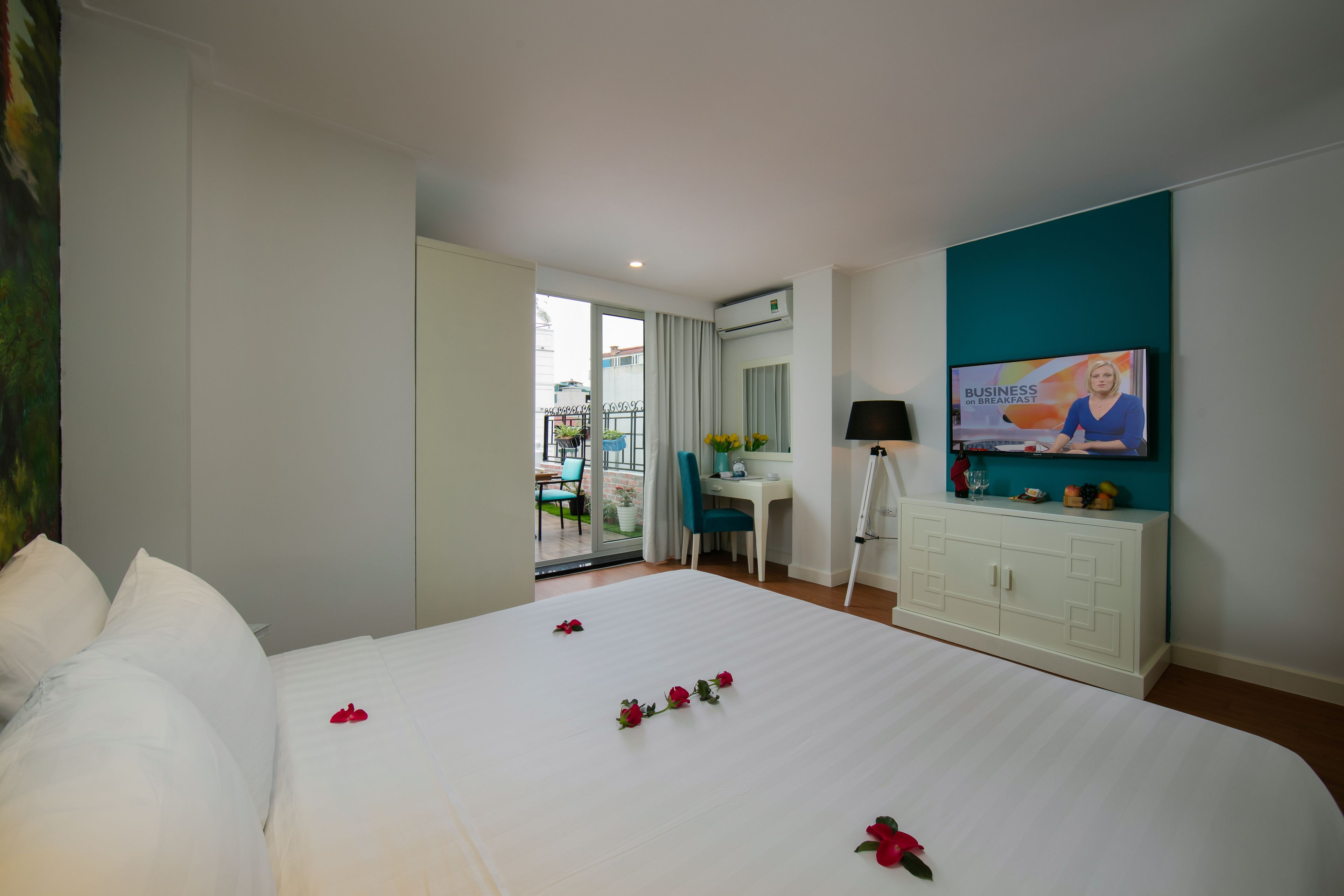 Habitación de hotel con una cama grande, un escritorio, un televisor y un balcón con vistas.