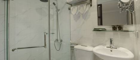 A modern bathroom with a glass shower enclosure, a white toilet, a sink, and a mirror with a towel rack above it.