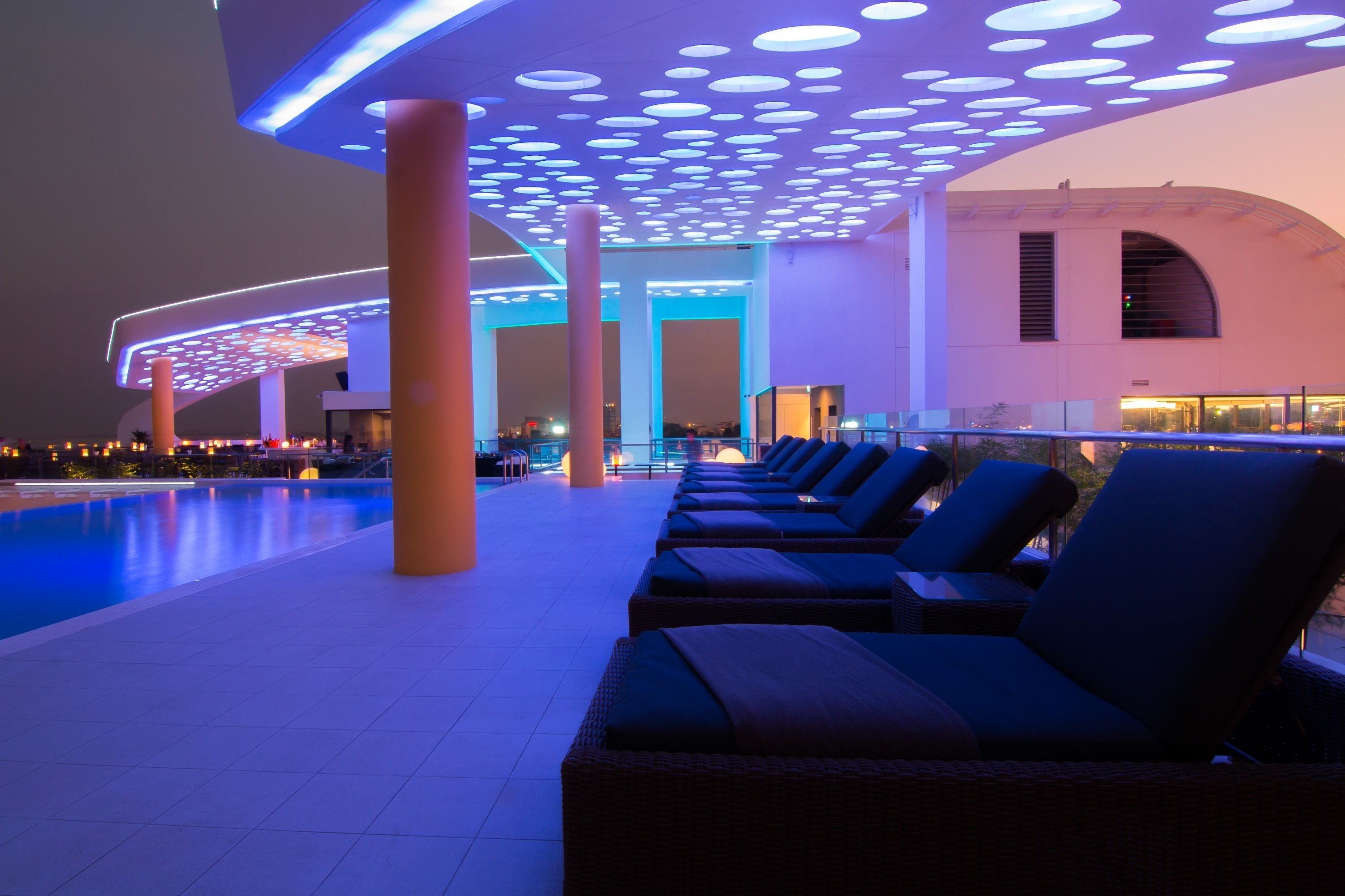 Area piscina moderna con poltrone relax e un design di soffitto originale.