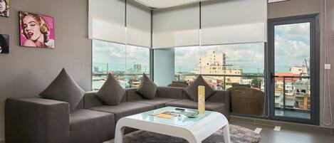 Una sala de estar moderna con un sofá modular, una mesa de centro de vidrio y amplios ventanales con vistas a la ciudad.
