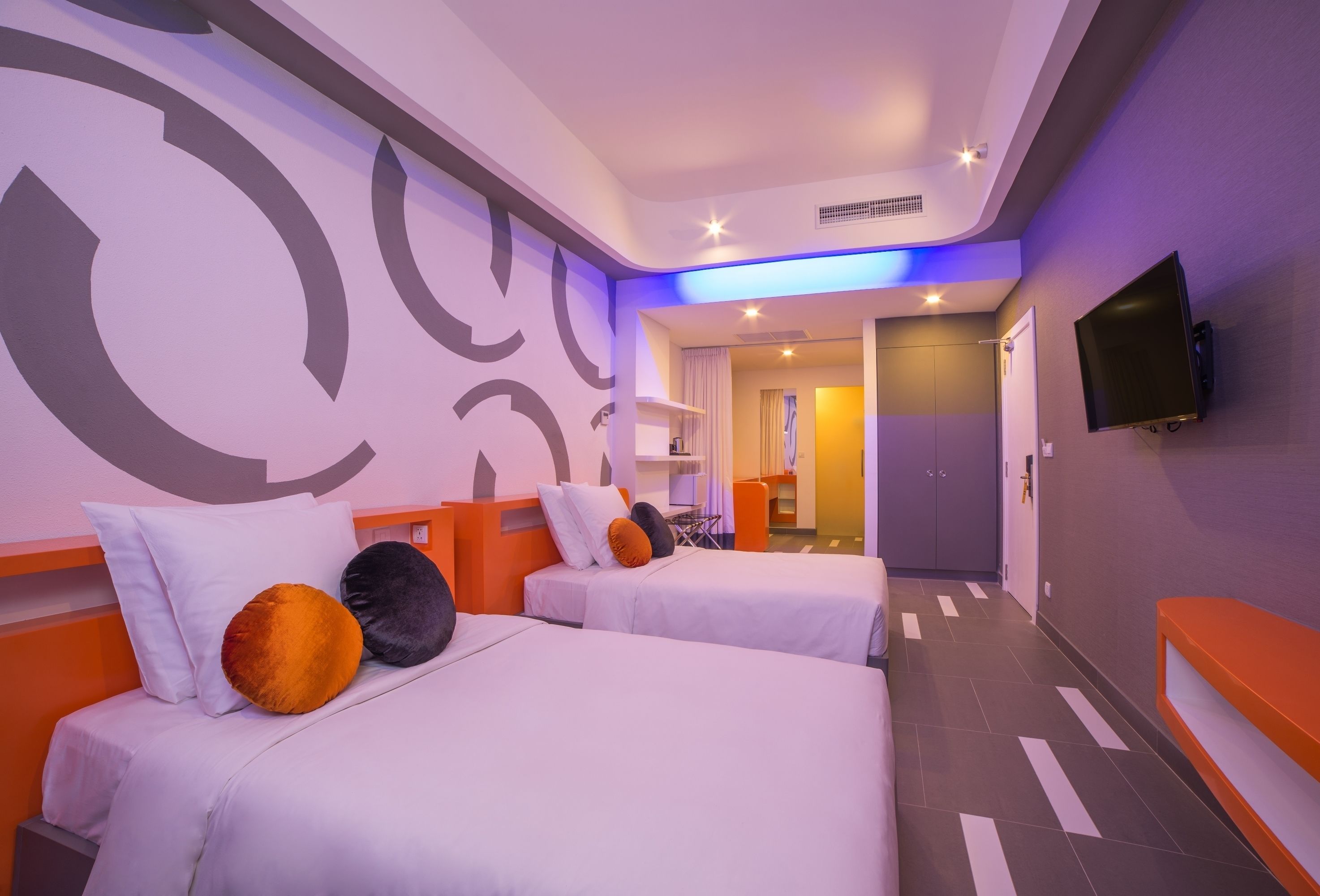Une chambre d’hôtel avec deux lits, une télévision et une salle de bain visible au fond.