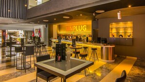Zona de bar moderna con un llamativo letrero que dice 'UNPLUG', taburetes y una variedad de botellas de licor.