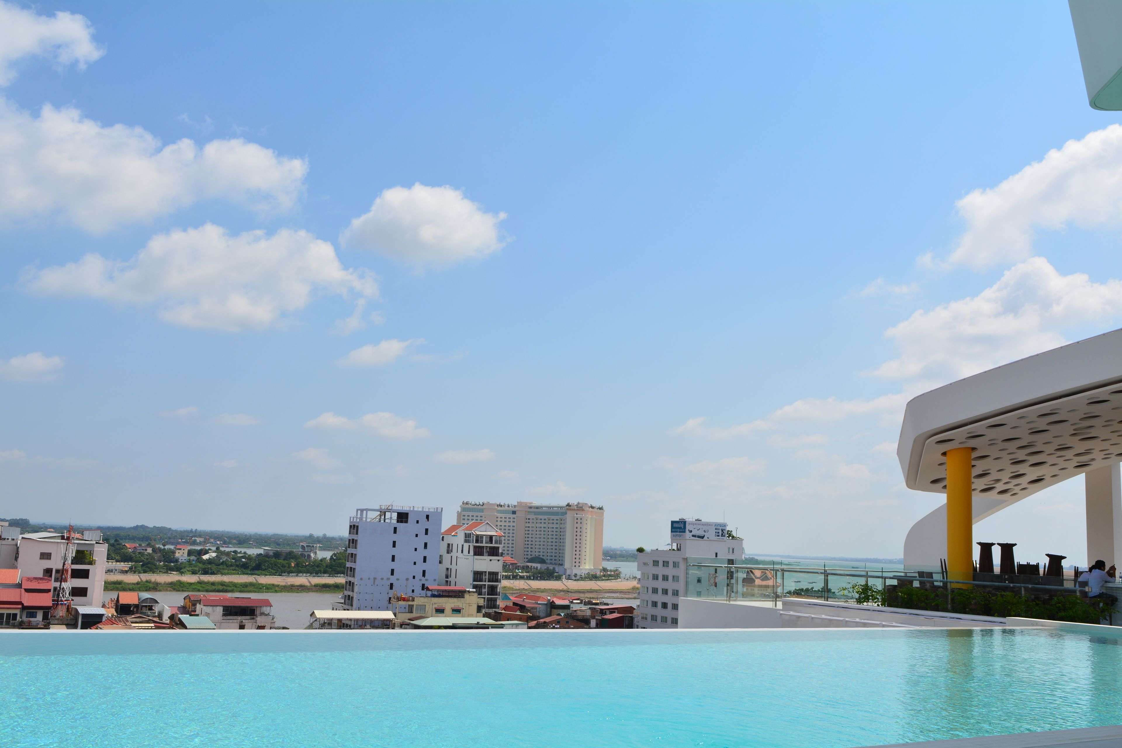 Una piscina en la azotea con vistas a la ciudad y una playa a lo lejos.