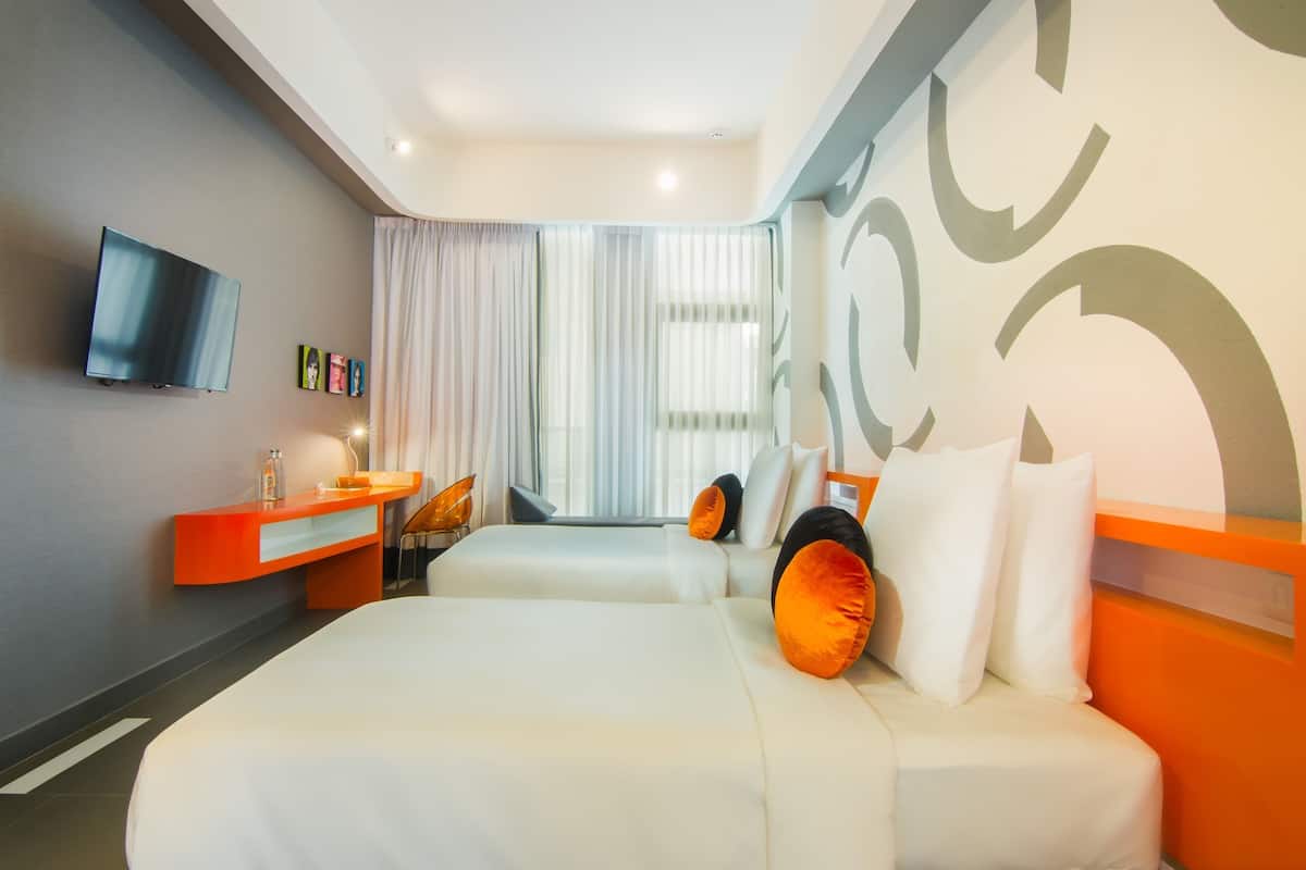 A modern hotel room with a large bed, a desk, and a television on the wall.