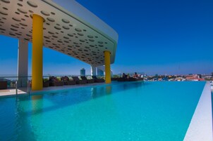 Zona de piscina con diseño moderno, que presenta un techo curvo y pilares amarillos.