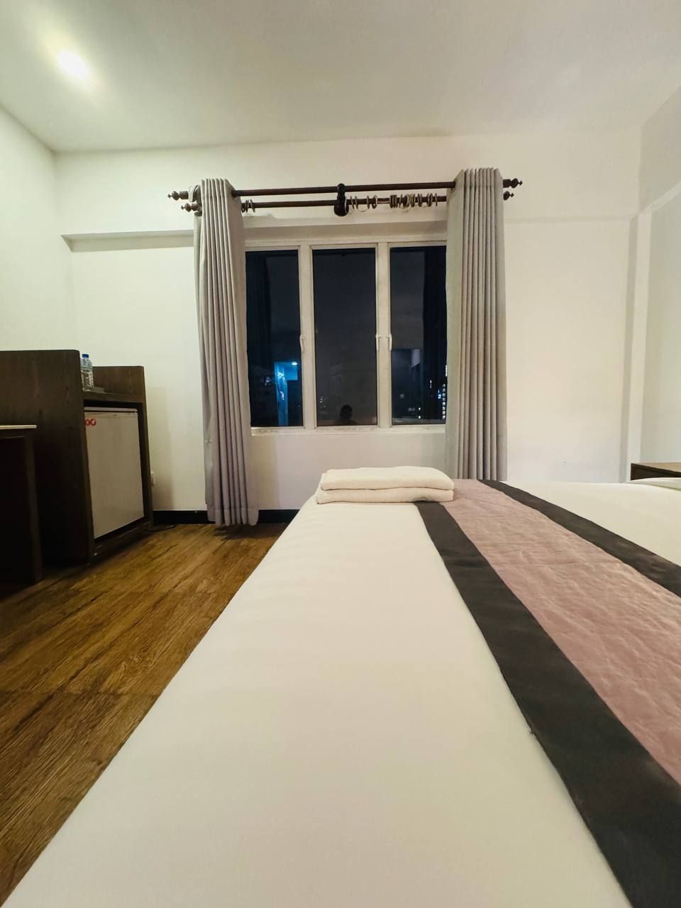 A hotel room with a bed, a desk, and a window with curtains.