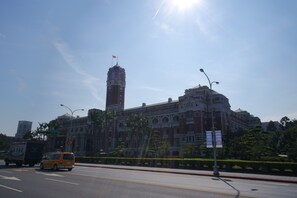 A large building with a prominent tower and a flag on top, surrounded by greenery and a clear sky. - Angels' Hostel - Taipei Ximen (Taipei)