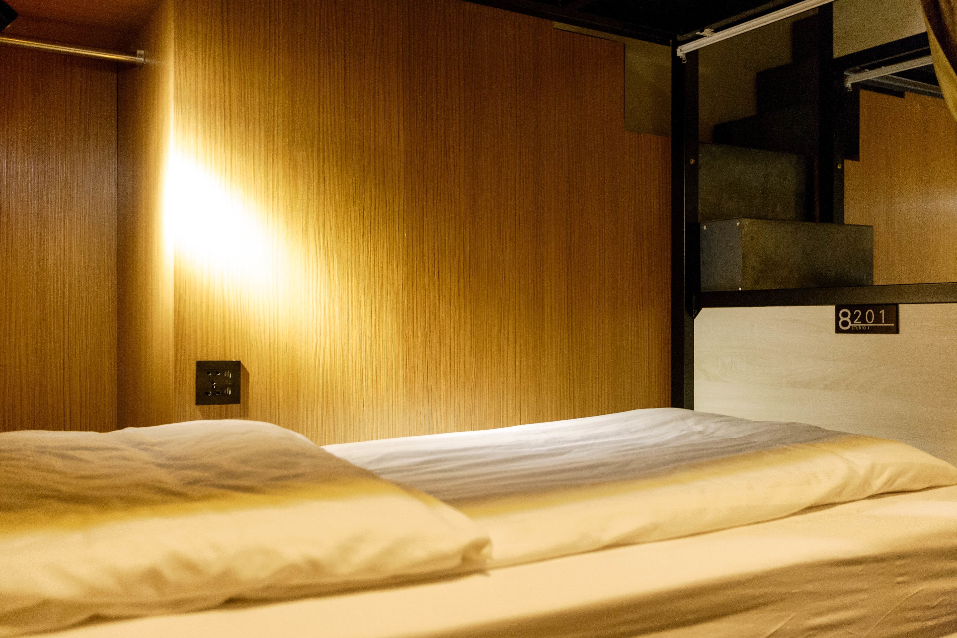 A single bed with a wooden headboard and a small bedside table with a lamp.