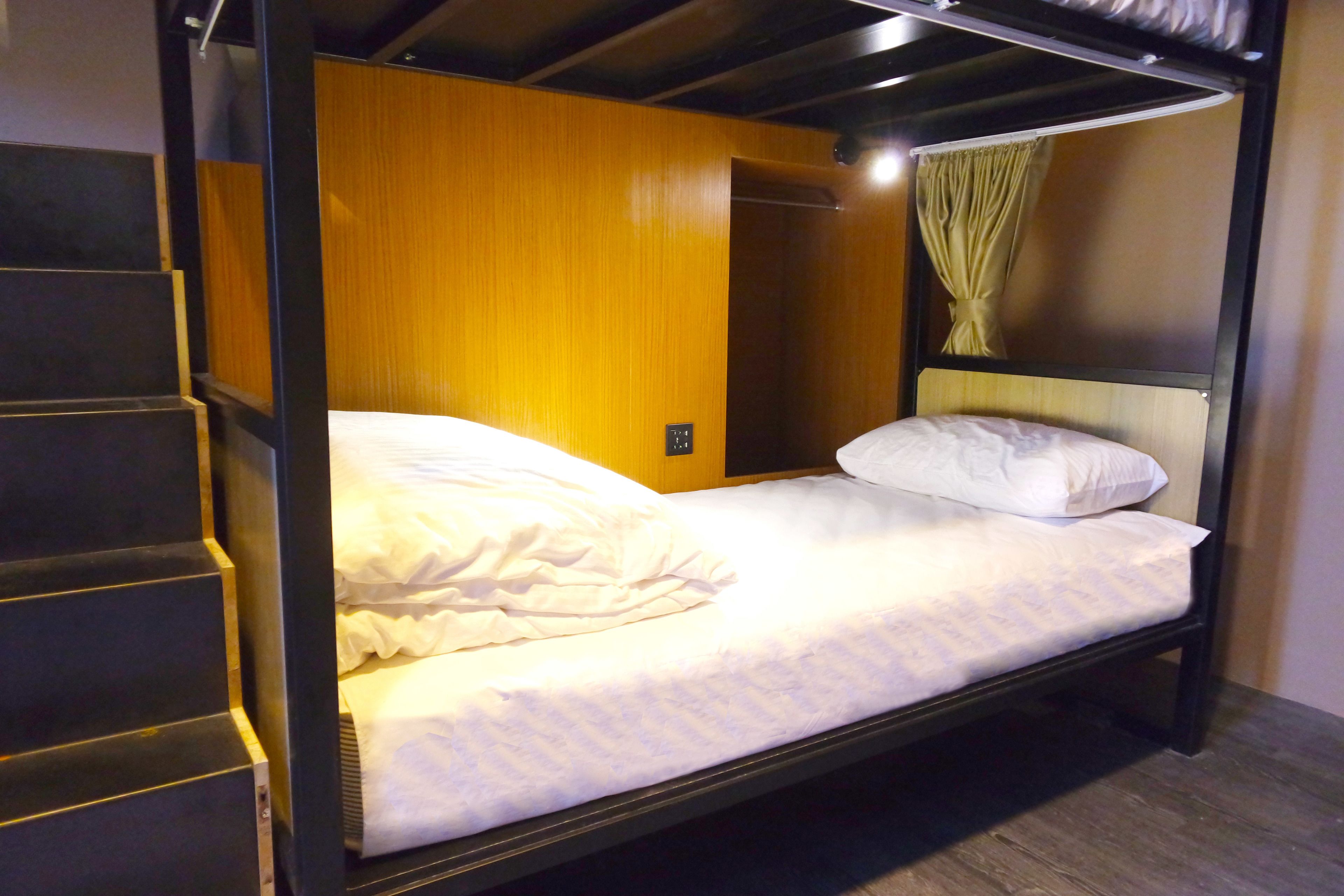 Un lit superposé avec une tête de lit en bois et un rideau.
