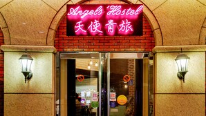 A hotel entrance with a neon sign, glass doors, and two wall-mounted lights. - Angels' Hostel - Taipei Ximen (Taipei)