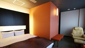A hotel room with a bed, a small table, a chair, and a wall-mounted light. - Palude Kushiro (Kushiro)
