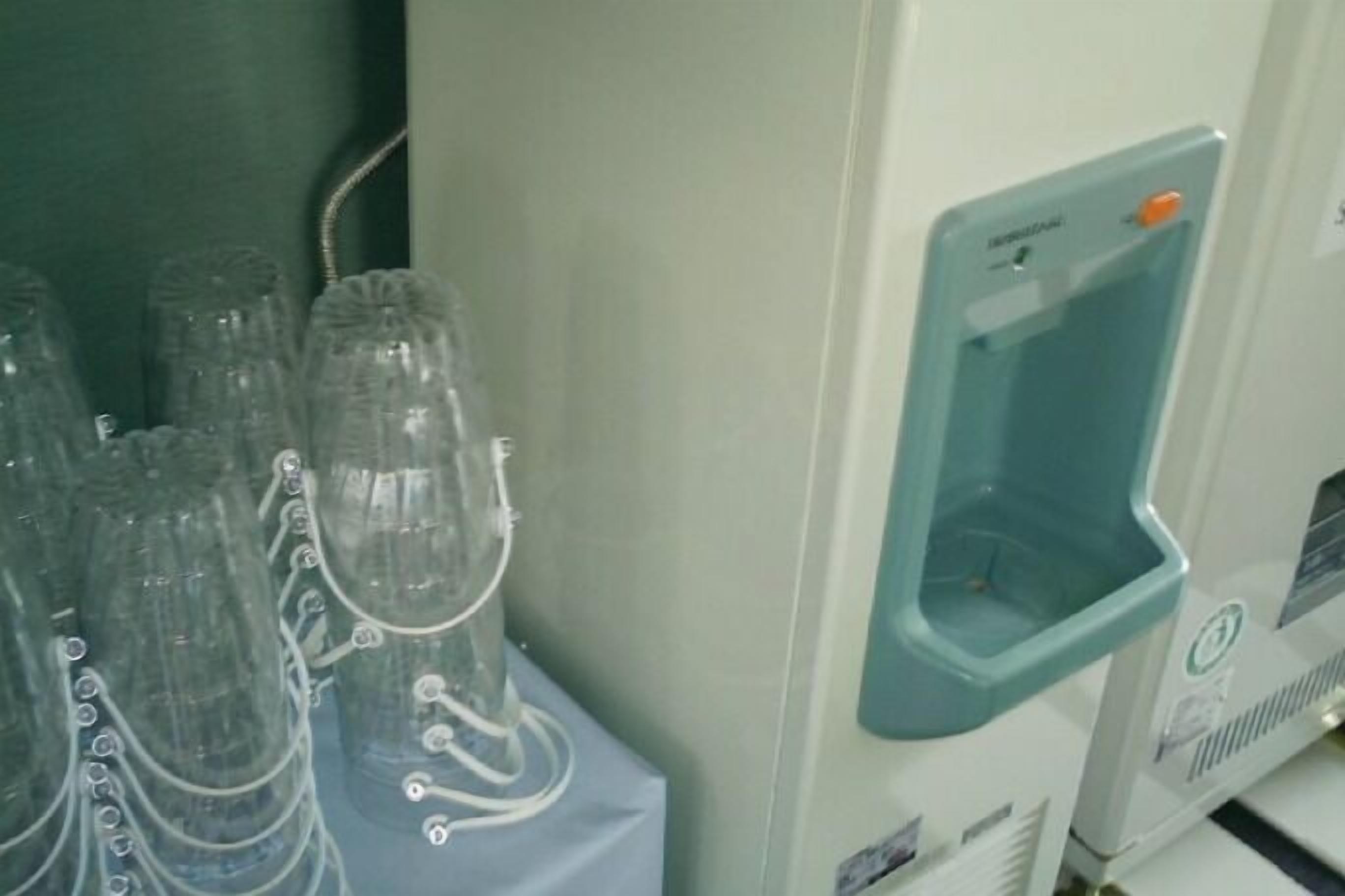 Montaje de laboratorio con varios recipientes de vidrio y un dispensador de agua.