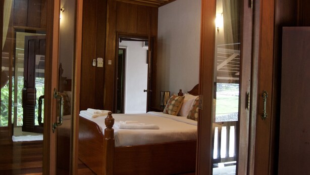 Een houten kamer met een bed, een deur en een lamp.