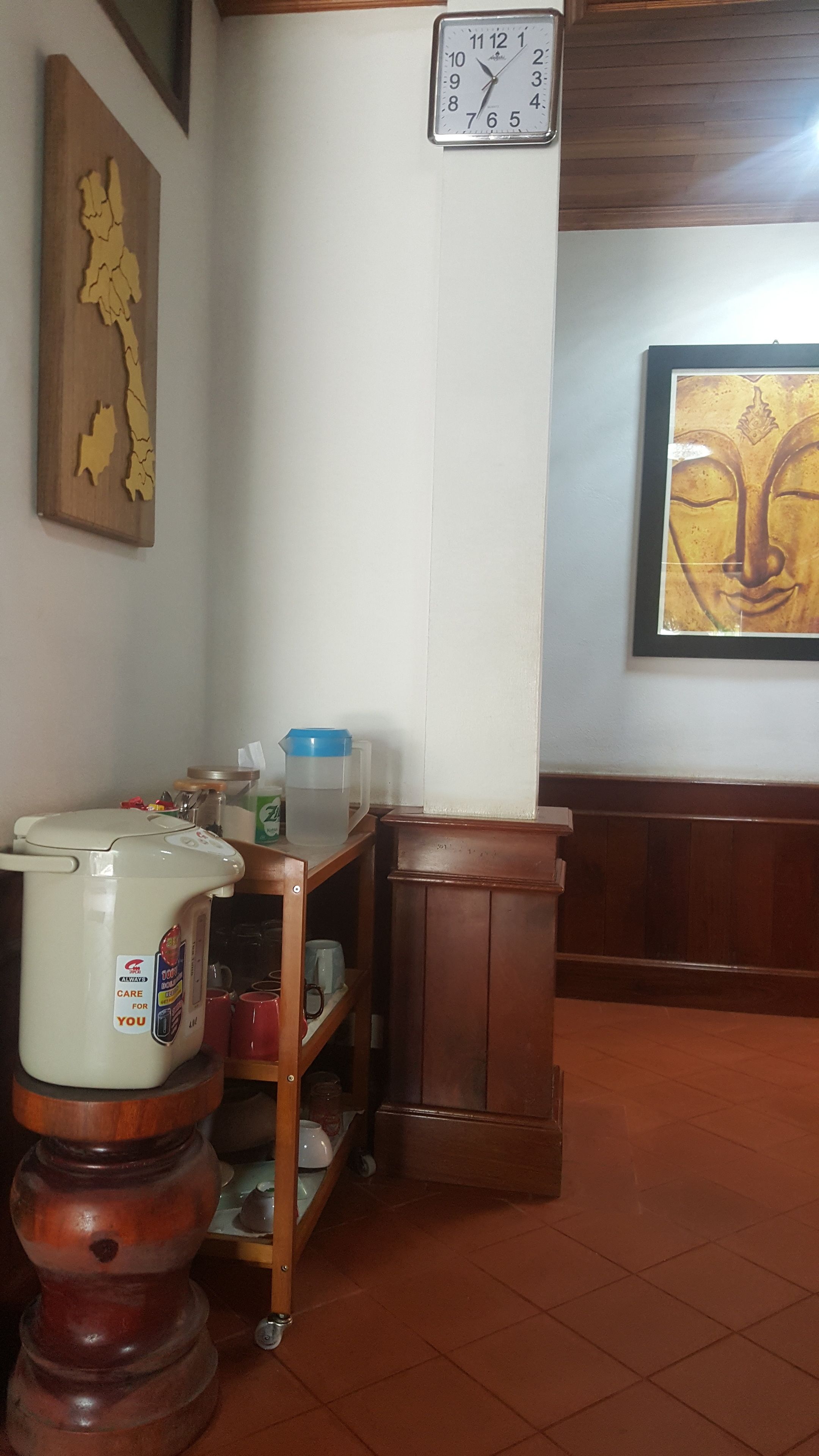 Una cocina con cafetera, un reloj y una alacena con utensilios de cocina.