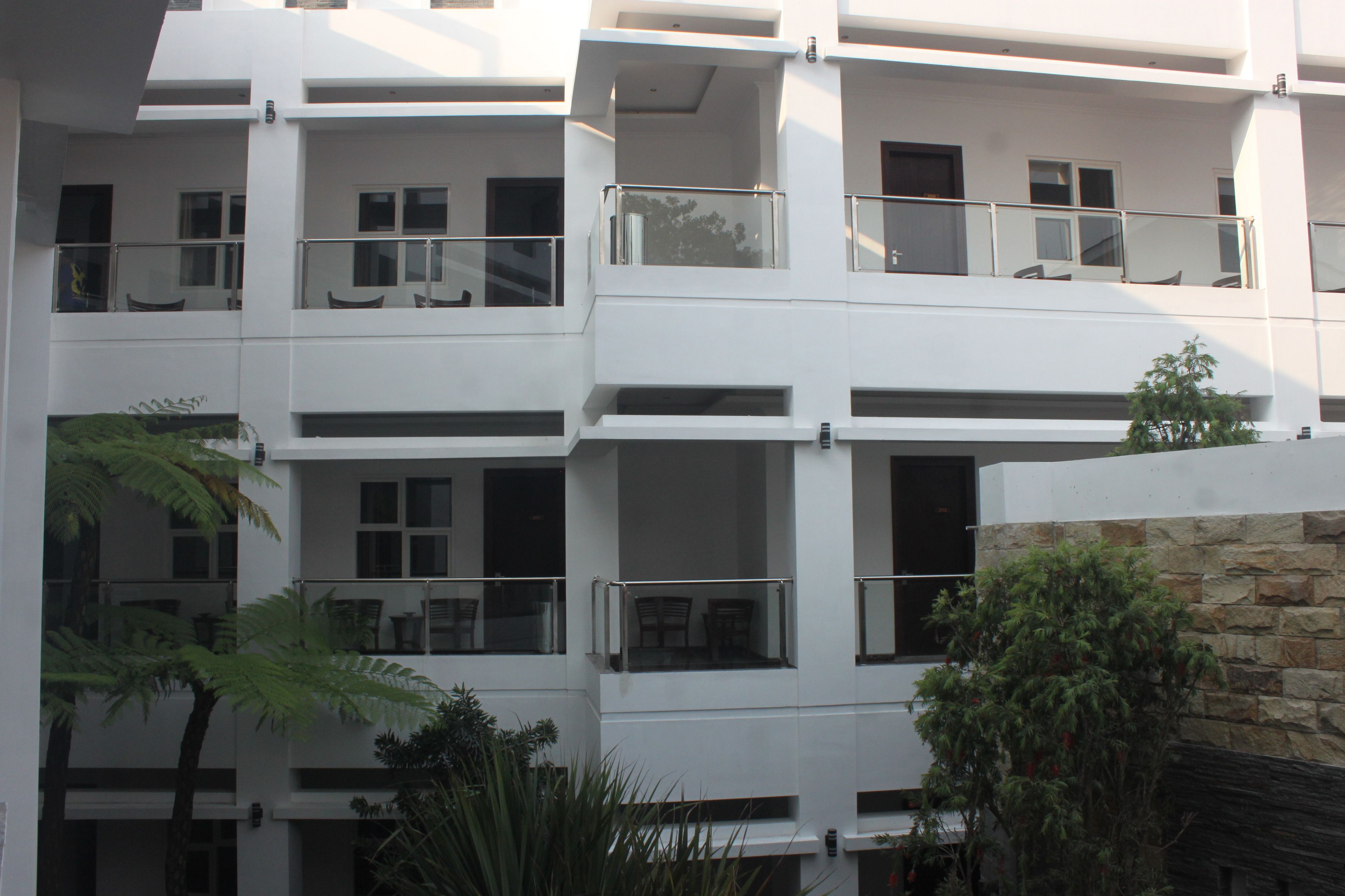 A multi-story building with balconies, large windows, and a stone facade.