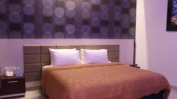 Ein modernes Hotelzimmer mit einem großen Bett, einem Kopfteil mit kreisförmigem Muster, einem Nachttisch und einem Wandbild.