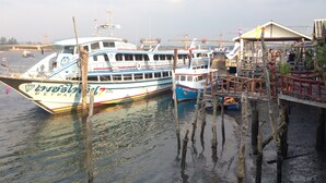 A dock with boats, wooden walkways, and a covered area with people. - Non Du Lay Guesthouse (Ko Lanta)