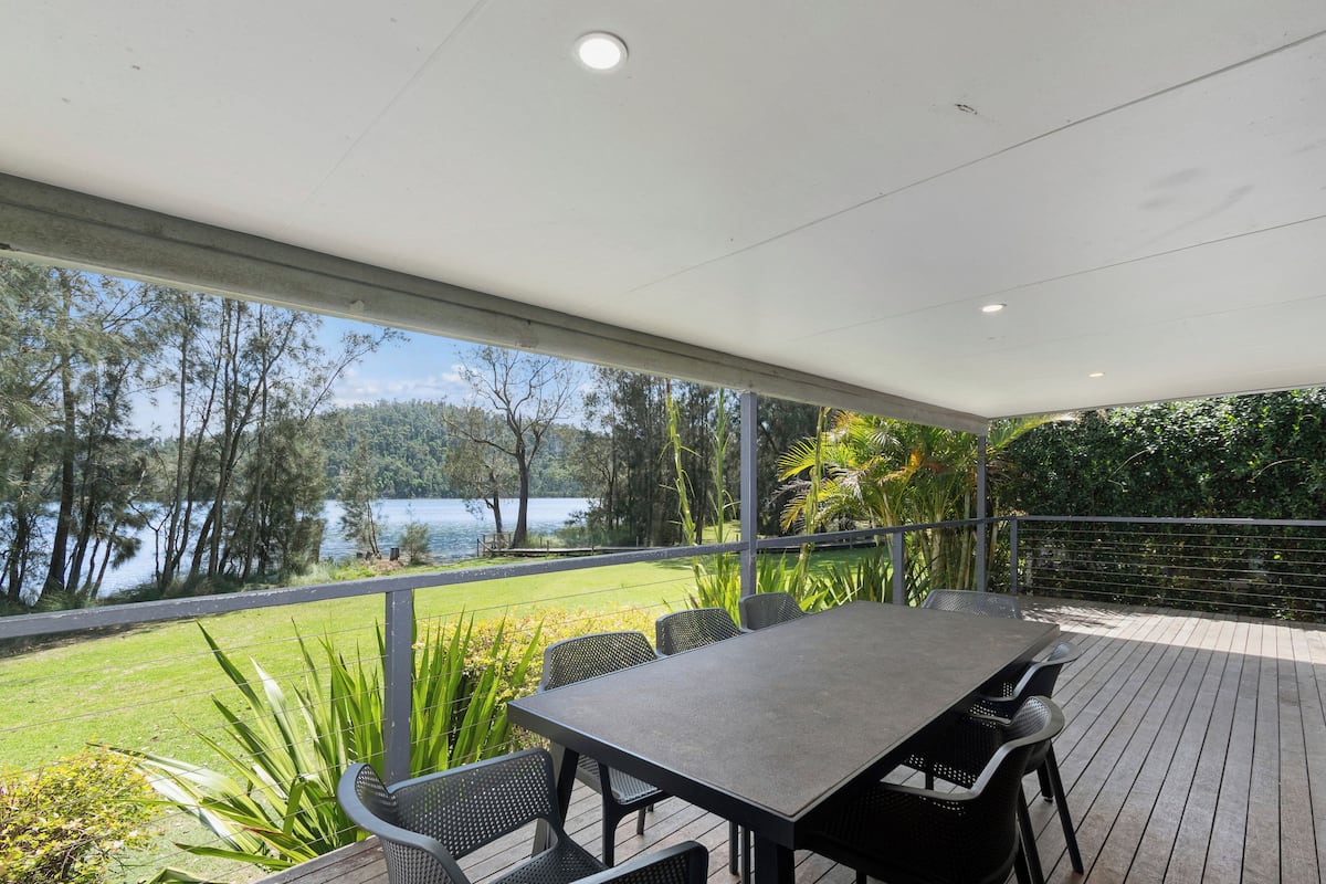 Une terrasse extérieure avec une table et des chaises, donnant sur un lac et une végétation luxuriante.