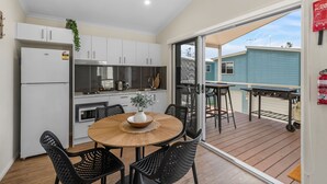 A modern kitchen with white cabinets, a built-in oven, and a dining area with a round wooden table and black chairs.