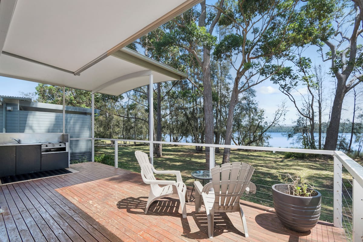 Une terrasse dotée de mobilier d’extérieur et d’un barbecue, avec vue sur un lac.