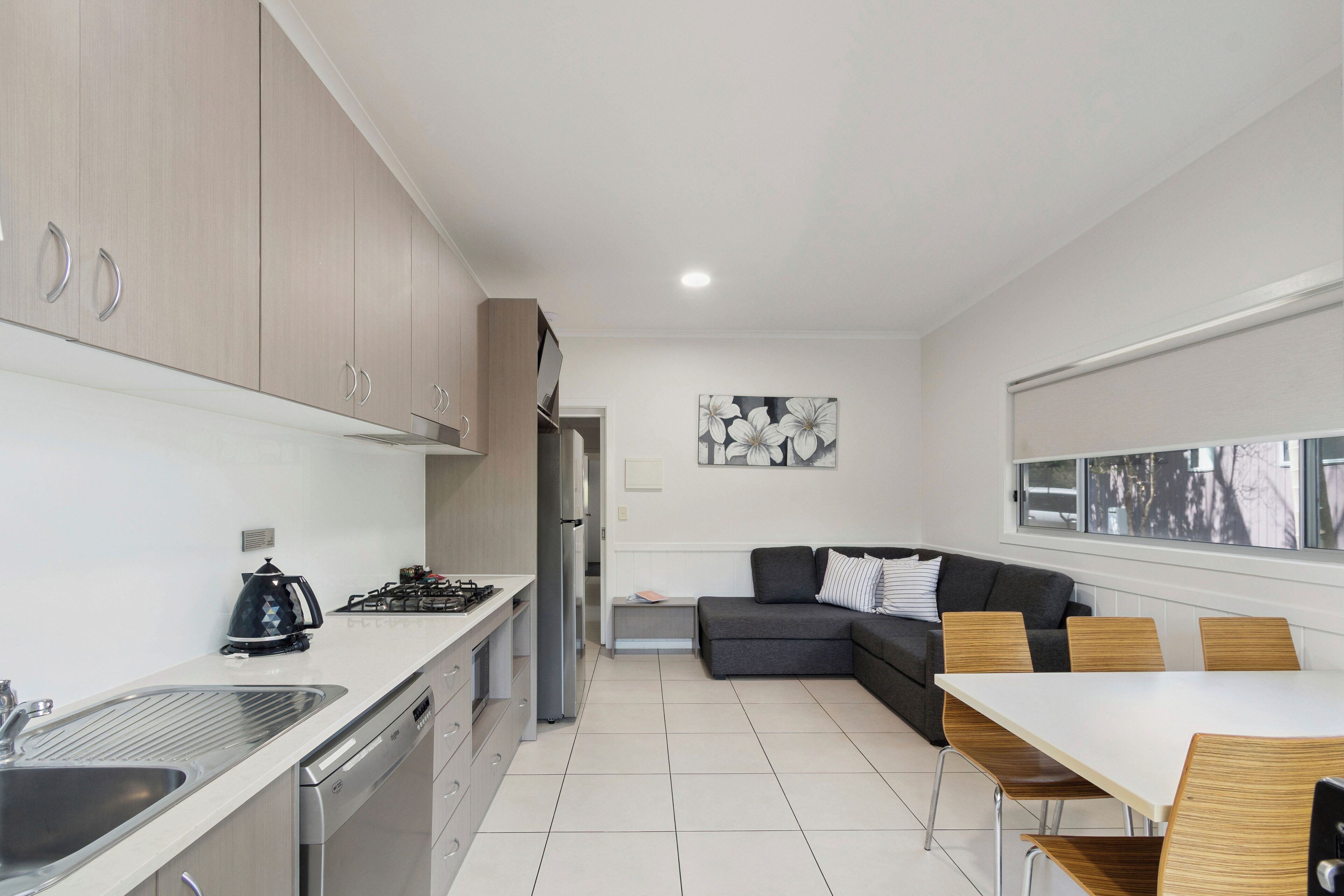 Une cuisine moderne avec un coin repas, comprenant une cuisinière intégrée, un évier et une table à manger avec des chaises.