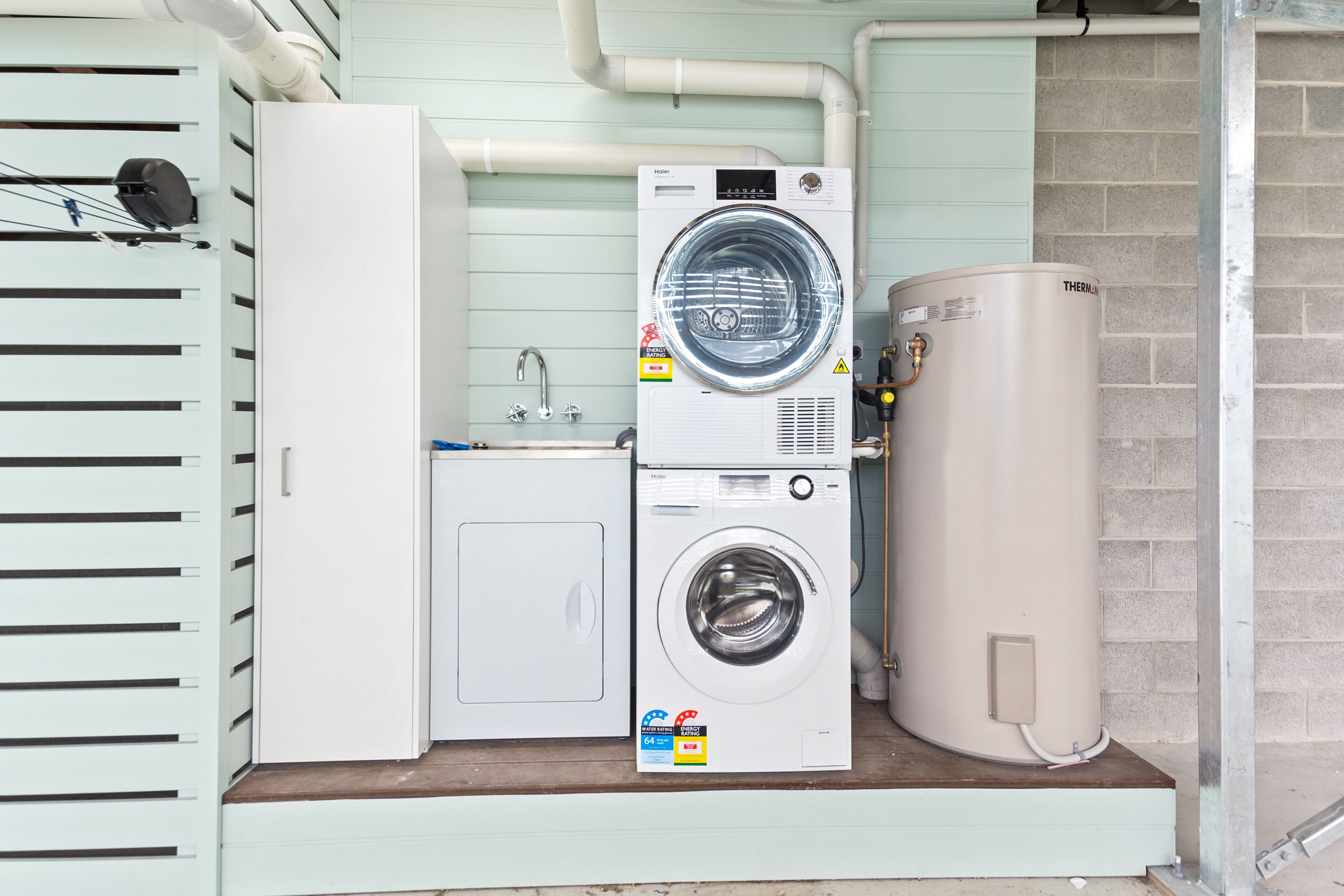 Een wasserette met een wasmachine, droger, boiler en een wasbak.