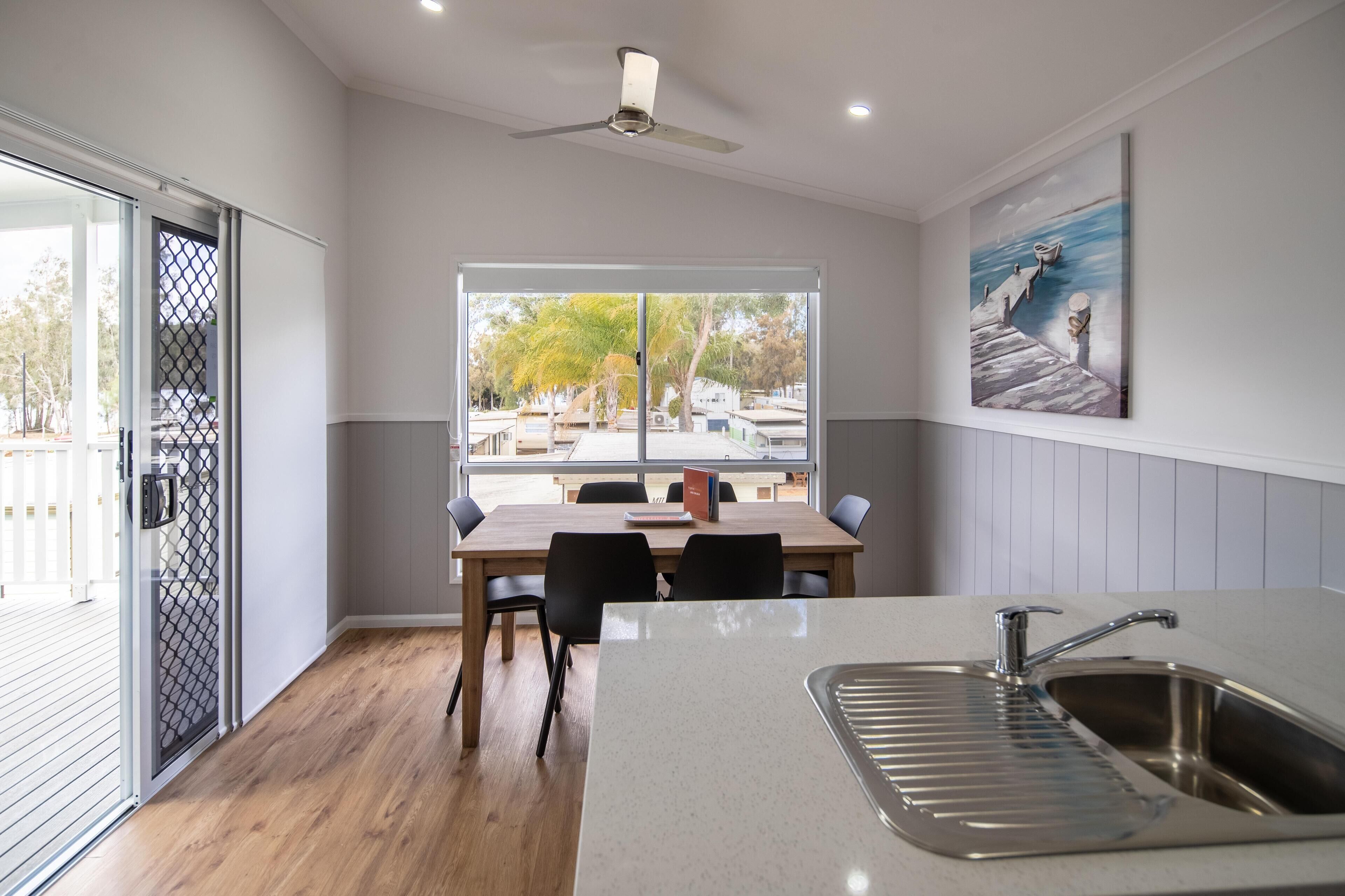 A modern kitchen with a large window, a dining table, and a sink.