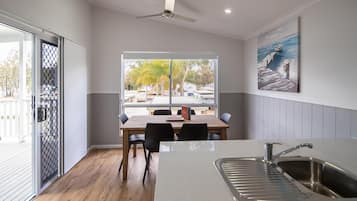 A modern kitchen with a large window, a dining table, and a sink.