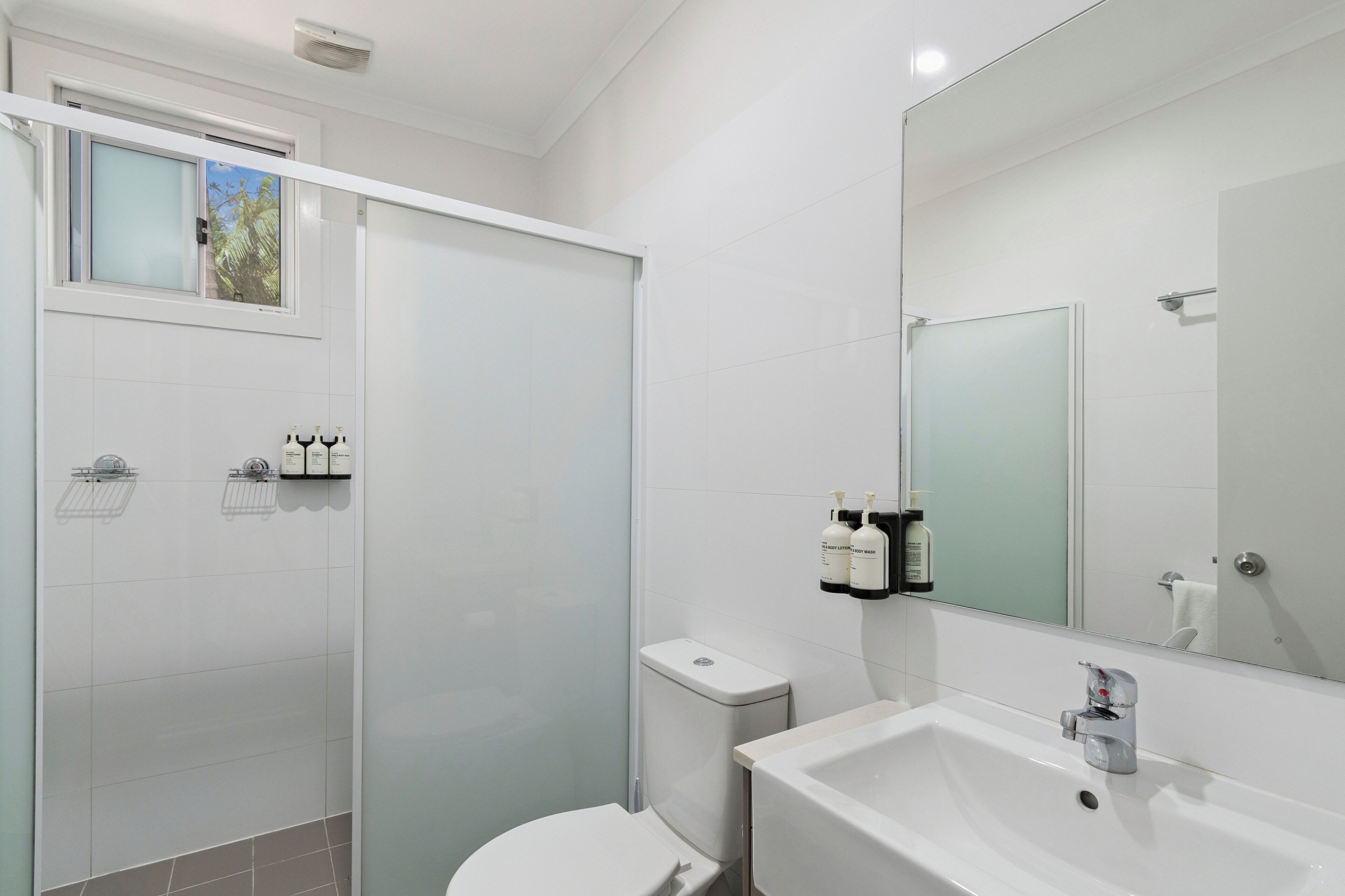 Ein modernes Badezimmer mit Dusche, Toilette, Waschbecken und Spiegel.