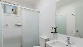 Ein modernes Badezimmer mit Dusche, Toilette, Waschbecken und Spiegel.