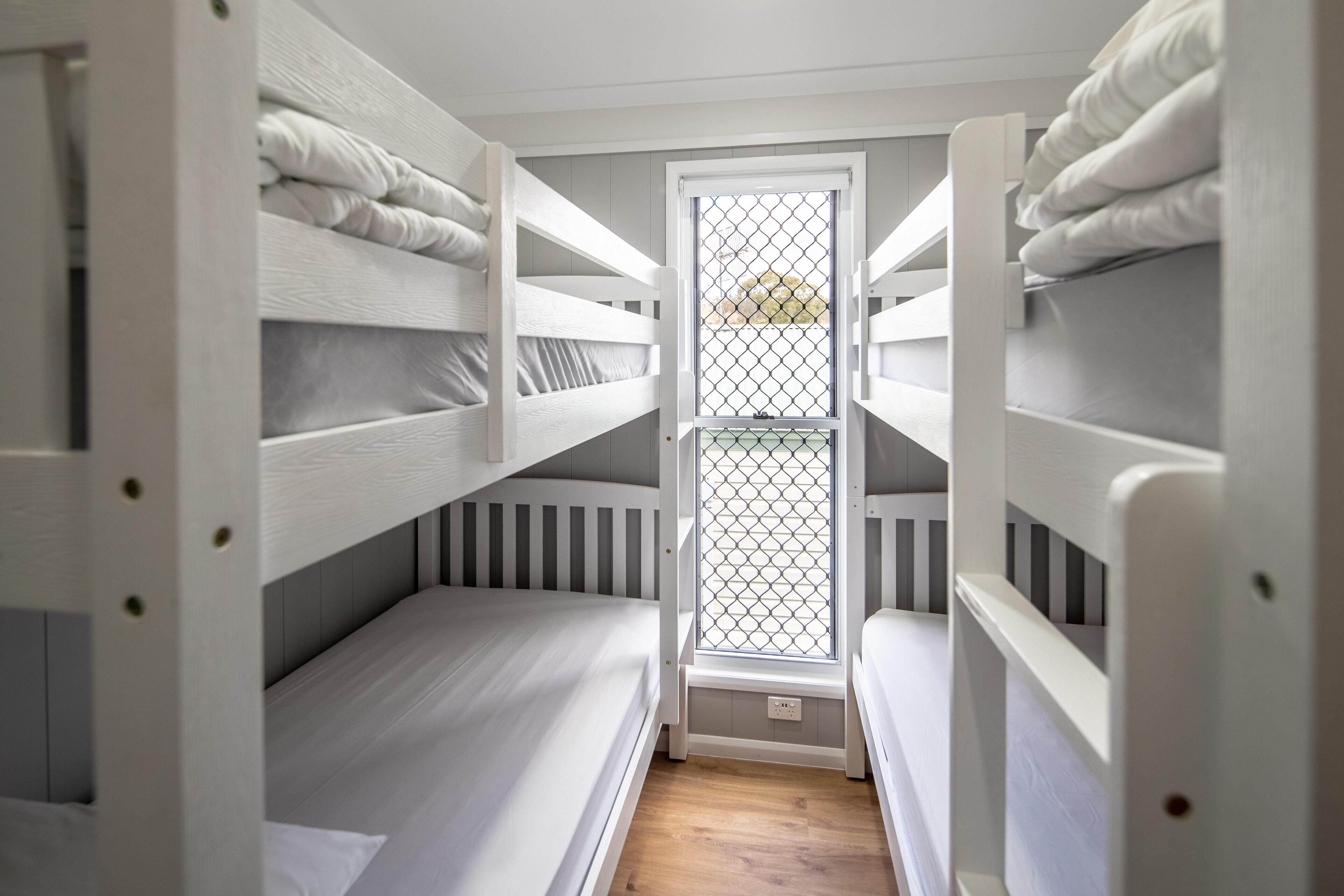 A bunk bed room with a window and a door.