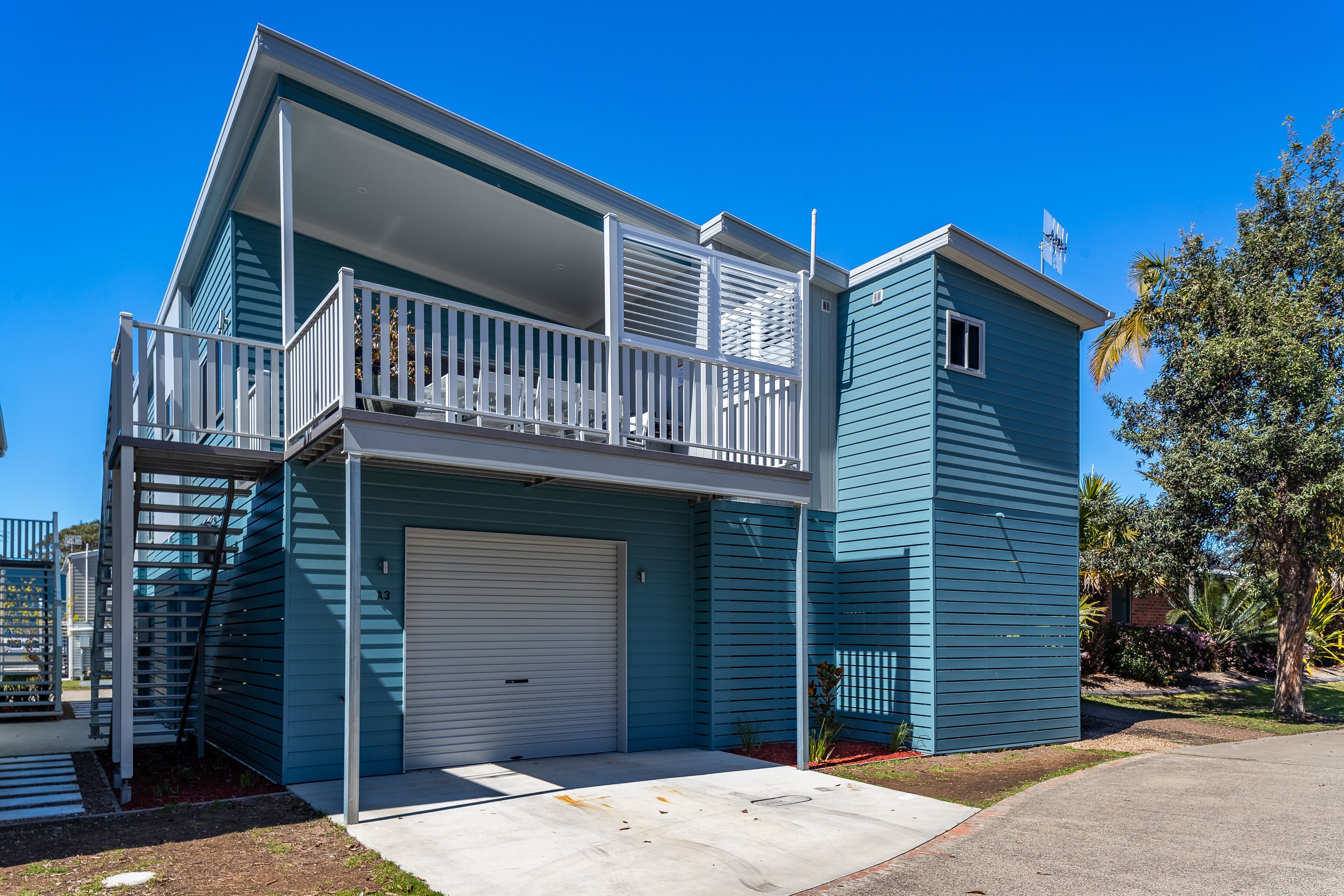 Un immeuble de deux étages doté d’un balcon, d’un garage et d’une petite fenêtre.