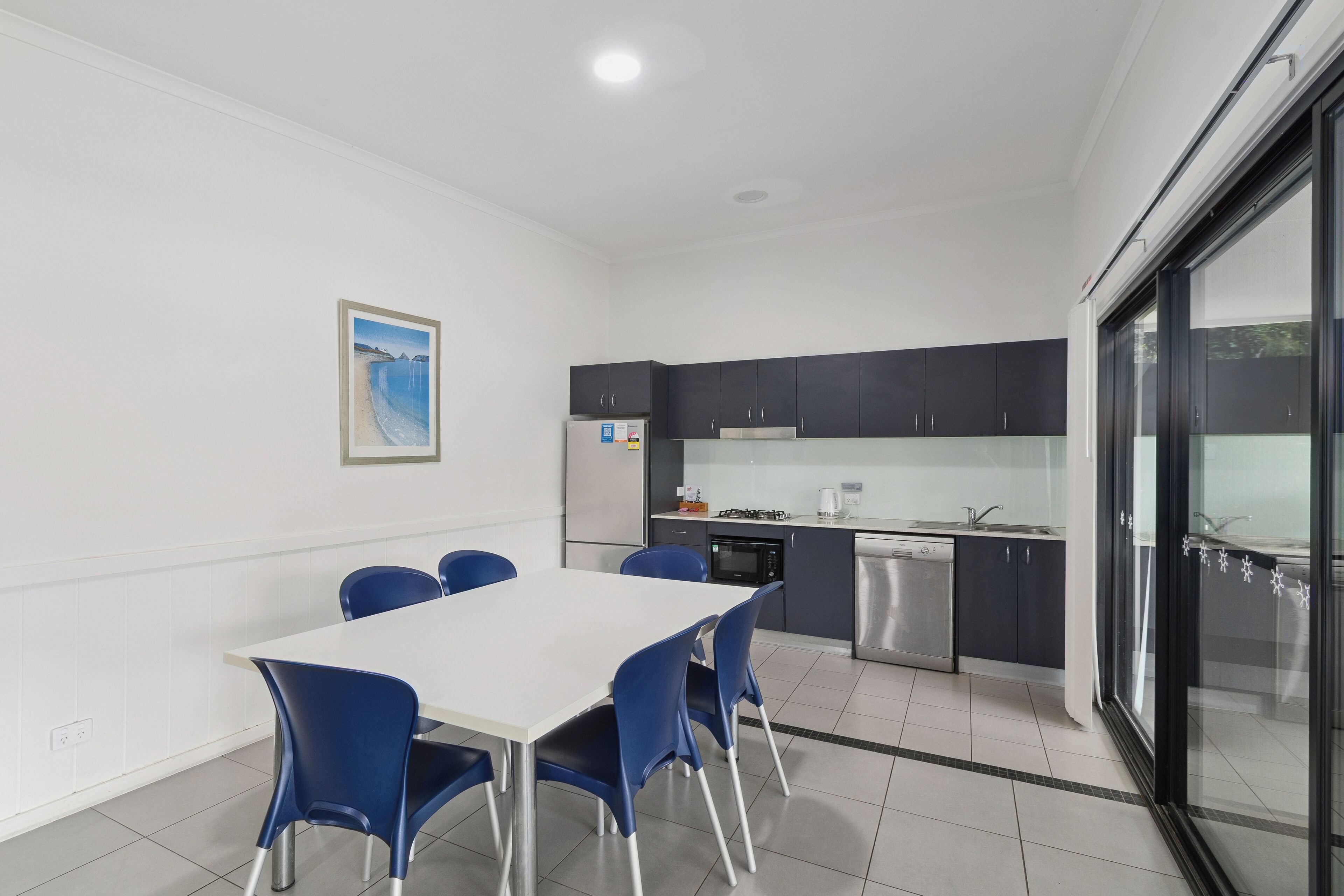 A modern kitchen with dark cabinets, a white countertop, and a stainless steel dishwasher.