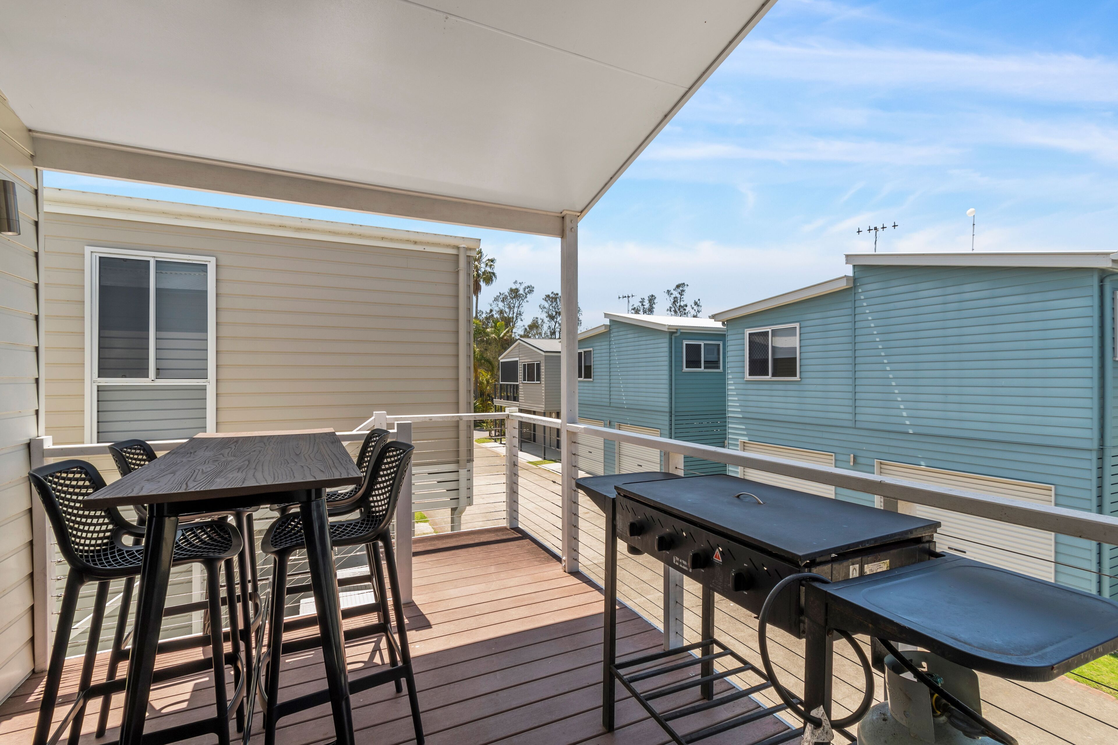 A covered outdoor area with a barbecue grill, a table, and chairs.