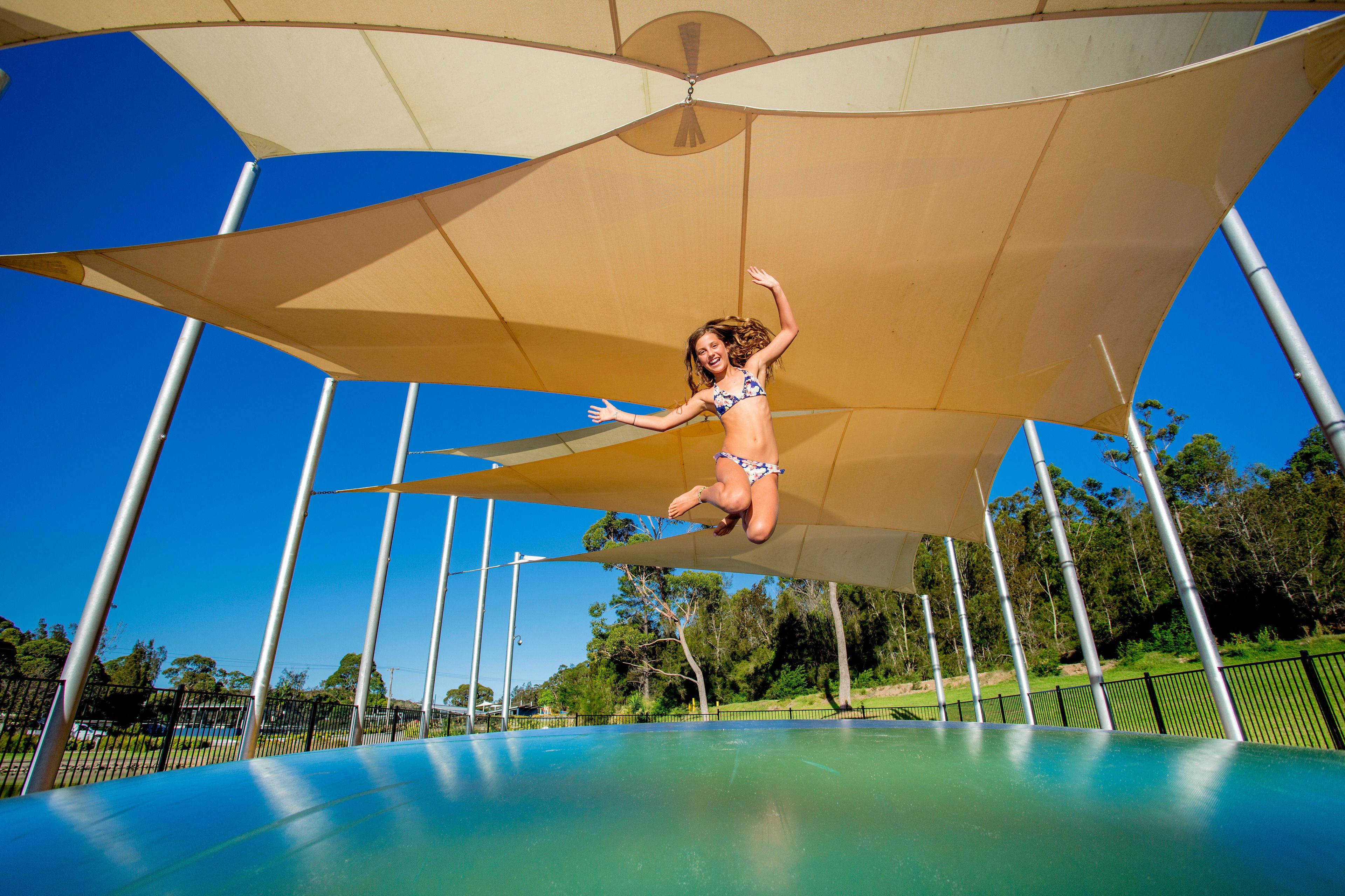 A person jumping on a trampoline under a large canopy.