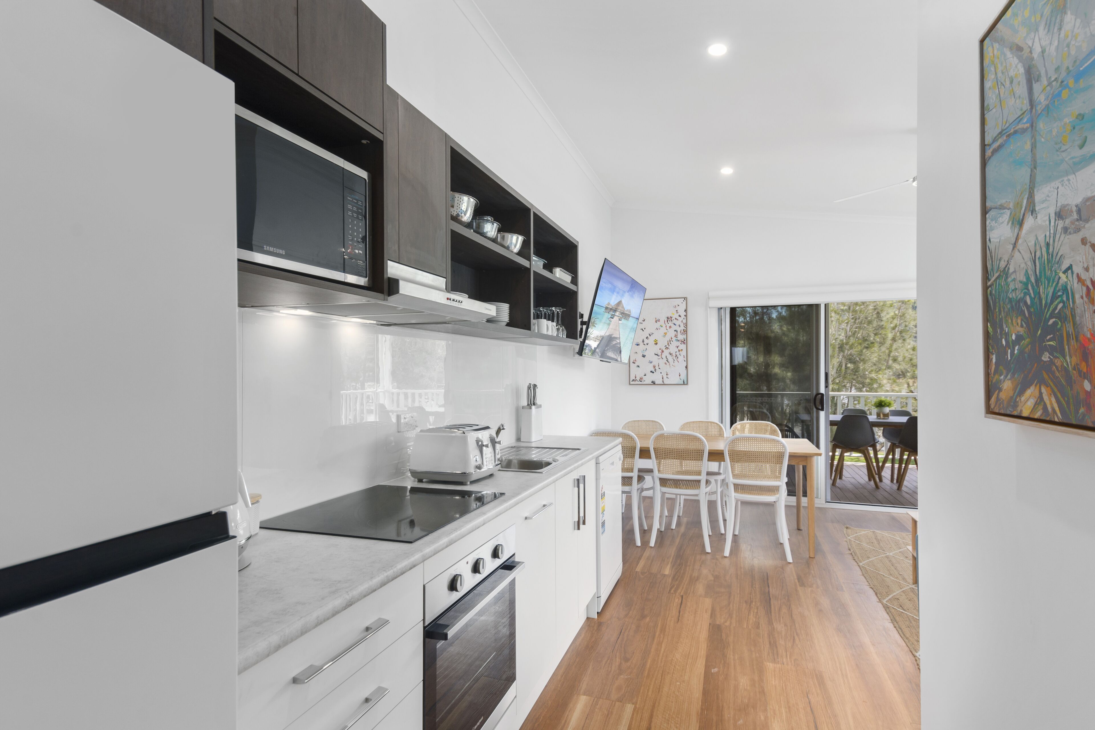 A modern kitchen with a microwave, oven, and dining area with chairs and a table.