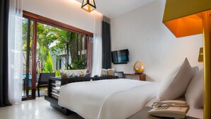 A modern hotel room with a large bed, a desk with a telephone, a TV, and a view of lush greenery through a sliding glass door. - Apsara Residence Hotel (Siem Reap)