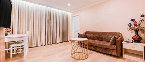 A modern living room with a sofa, a round coffee table, and a TV.