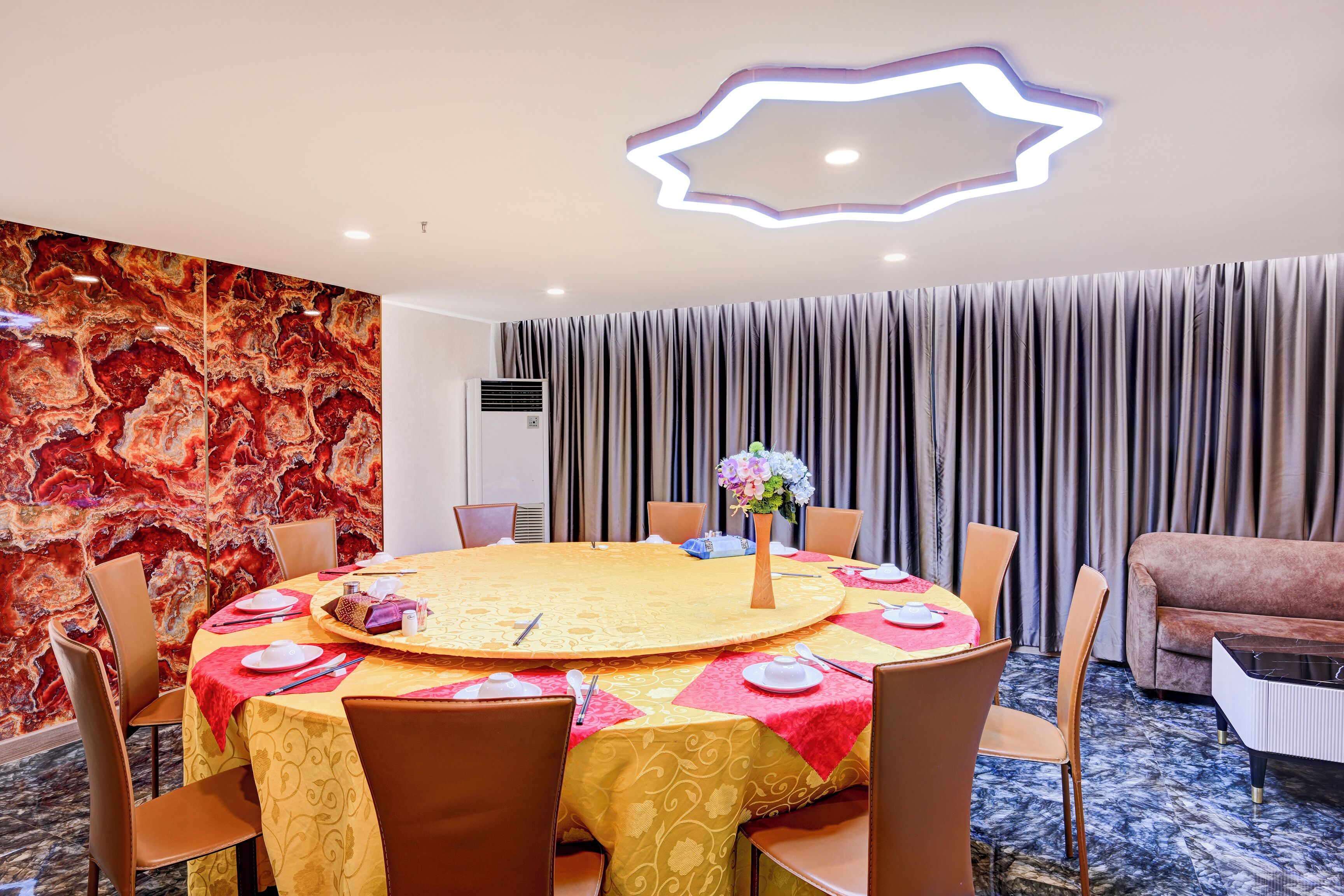 A conference room with a round table, chairs, and a floral centerpiece.