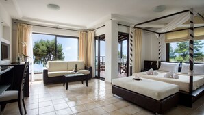 A hotel room with a bed, a sofa, a desk, and a balcony with a view of trees. - Elani Bay Resort (Kassandra)