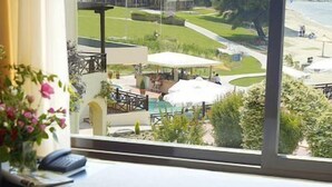 A hotel room with a view of a golf course and beach. There is a laptop, a cup of coffee, and a pitcher on the table. - Elani Bay Resort (Kassandra)